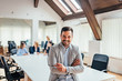 © bnenin - Portrait of a smiling handsome businessman with crossed arms in a meeting room.