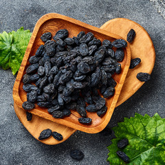 Wall Mural - Black raisins on gray background. Top view of dried grapes.