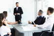 © opolja - Businessman presenting to colleagues at a meeting.