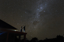 Couple On Rooftop Watching Mliky Way And Catching Stars In The Night Sky On Bali Island
