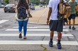 © Susan Vineyard  - Back to school - the backs of college students crossing urban crosswalk with backpacks - ethnic diversity and casual dress with cars driving by