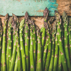 Wall Mural - Seasonal harvest produce . Flat-lay of raw uncooked green asparagus over rustic wooden tray background, top view, close-up, square crop. Local market food concept