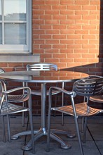 Outdoor Patio Seating With Aluminum Chairs And Table And Brick Wall Reflection