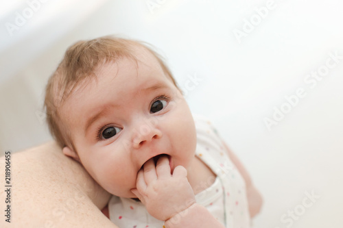Fototapeta From above shot of cute baby sucking fingers and looking at camera