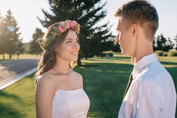 beautiful happy young wedding couple looking at each other in park