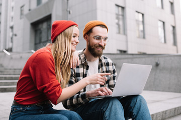 Collaborate, business, teamwork. Creative freelancers planning startup project using laptop computer. Smiling and positive hipsters working together, woman shows a finger on display.