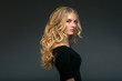 © Utkamandarinka - Blonde hairstyle woman beauty with long curly blonde hair over dark background