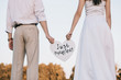 cropped shot of young wedding couple holding heart with just married inscription