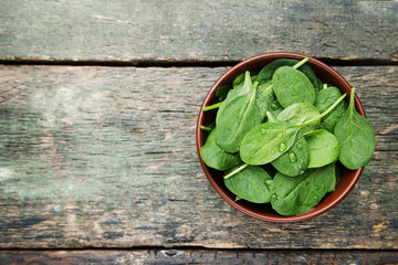 Spinach leafs in bowl on grey wooden table