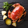 © FomaA - tasty boiled whole brown crab with sauce, lemon and parsley on a stone board close-up. top view