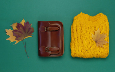 Wall Mural - Female orange knitted sweater, leather bag and autumn leaves on dark green background top view flat lay. Fashion Lady Clothes Set Trendy Cozy Knit Jumper Autumn accessories. Female fashion look