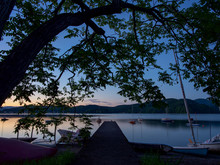 湖畔にて、夕焼けも終わり、空には木々のシルエットが広がり、桟橋が湖面に伸びています。