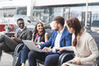© xartproduction - Group of happy diverse male and female business people team in formal gathered around laptop computer in bright office against the background of a glass building