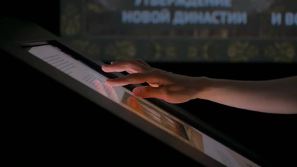 Woman using interactive touchscreen display at modern history museum. Education and technology concept