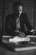 © monchak - Black and white portrait of handsome stylish man with dark hair and beard in jacket. Man with camera in his hands. Brick wall on background