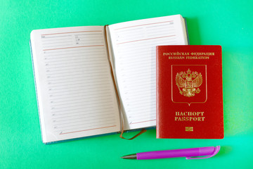 russian passport, open notebook and pen on a colored background