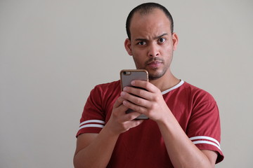 Man in Maroon t shirt emotive face smartphone