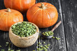 Bowl with pumpkin seeds and small pumpkin on a rustic table. Selective focus.