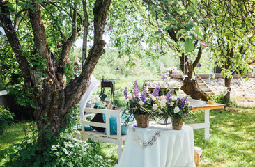 Wedding bouquets on a table with a white tablecloth and a book under a tree on a sunny day