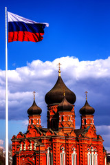 Church with black domes under the flag of Russia against the sky with clouds. assumption cathedral in Tula