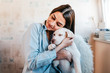 © bnenin - Beautiful brunette girl hugging her puppy at home. Close-up.