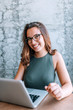 © bnenin - Portrait of cheerful brunette woman with glasses using laptop.