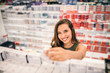 © bnenin - Young woman holding cosmetics in her hand in supermarket.