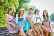 © karepa - Oktoberfest Freunde in Lederhosen und Dirndl trinken Bier an der Isar