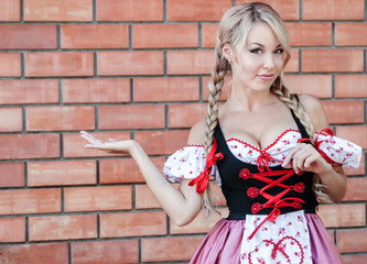 Beautiful young woman on stone background in Octoberfest dress.
