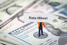 FED Consider Interest Rate Hike, World Economics And Inflation Control, Miniature Man Holding Rate Hikes Sign Standing On US Federal Reserve Emblem On Dollars Banknote