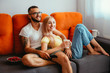 Happy young couple watching TV series together at home