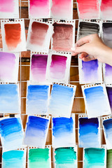 Wall Mural - watercolors swatch assortment background. ink dyes colors mix on paper. art painting and drawing. inspiration and creativity. artist skills practice. free space concept. woman hand choosing.