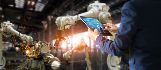 Fototapete - Industrial manager, engineer using tablet checking and controlling automation robot arms machine in intelligent factory industrial on monitoring system software.