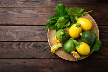 Wall Mural - Zucchini with leaves and flowers on dark wooden rustic background