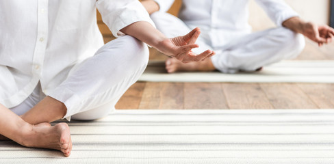 Wall Mural - cropped shot of elderly couple sitting in lotus position and practicing yoga together