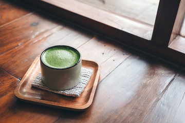 A cup of hot matcha latte on wooden floor