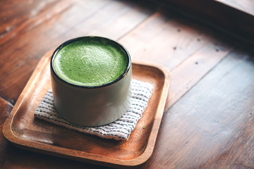 A cup of hot matcha latte on wooden floor