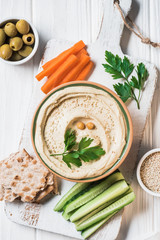 Wall Mural - top view of hummus with parsley, cut vegetables and pita bread on wooden tabletop