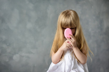 Wall Mural - little blonde girl with long hair combs her hair with a pink comb