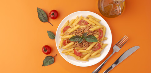 Wall Mural - Pasta Fettuccine Bolognese with tomato sauce and basil in white dish on the orange background.