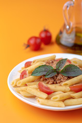 Poster - Pasta Fettuccine Bolognese with tomato sauce and basil in white dish on the orange background.