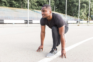 Sticker - Fit young African male athlete in sportswear racing alone down a running track on a sunny day