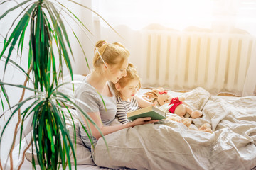 Wall Mural - happy family mother reading to daughter in bed. wonderful world of books for children. Acquaintance of the child with reading.	