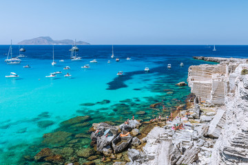 Beautifu panoramic view of rocky beach and blue lagoon with sailing boats. Favignana island