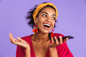 Poster - Cheerful african woman in dress talking by smartphone