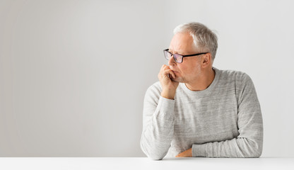 old age, problem and people concept - close up of senior man in glasses thinking