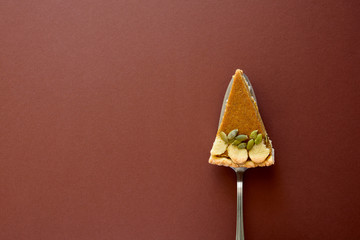 Wall Mural - Piece of homemade pumpkin pie with cinnamon on brown paper background. Thanksgiving day or Halloween holiday concept. Top view