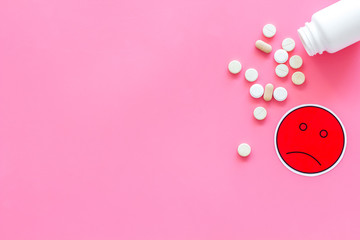 Sticker - Illness. Drug intake. Pills falling out of jar near sad face emoji on pink background top view copy space