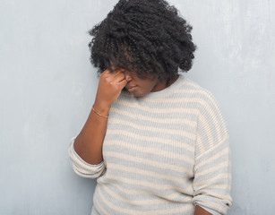 Sticker - Young african american plus size woman over grey grunge wall wearing a sweater tired rubbing nose and eyes feeling fatigue and headache. Stress and frustration concept.