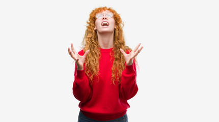 Canvas Print - Young redhead woman wearing red sweater crazy and mad shouting and yelling with aggressive expression and arms raised. Frustration concept.